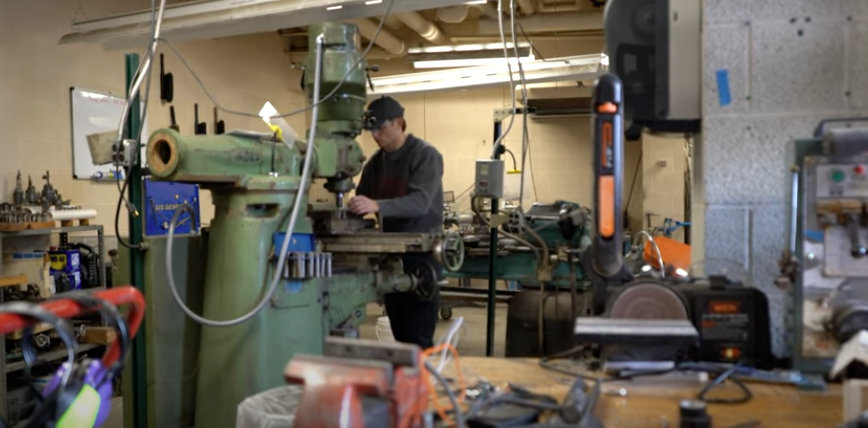 A student standing and working at a machine in the Electrical Engineering Lab at Alma College